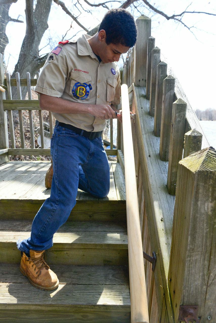A Scout working on a wooden handrail at Titusville Academy